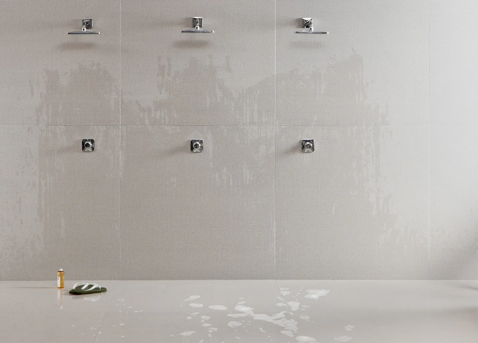 Drei Duschen mit Wand aus Mutina Pico Blue Dots Gris und Boden Pico Down Natural Gris