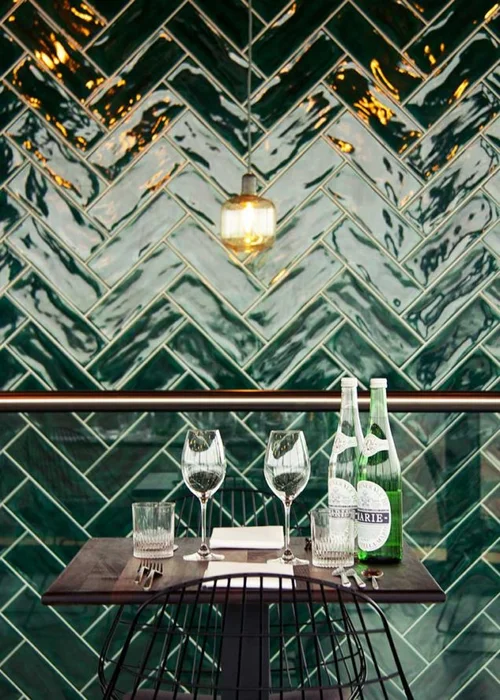 Green wall tiles in a herringbone pattern by Tonalite