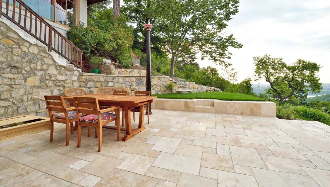 Terrasse am Hang aus Travertin Beige im Römischen Verband mit Holztisch
