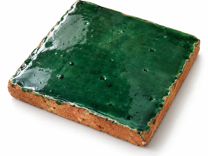 Materialstudie: handgemachte Zellige-Fliese mit rotem Terrakotta-Scherben, behauener Kante und dicker grüner Glasur